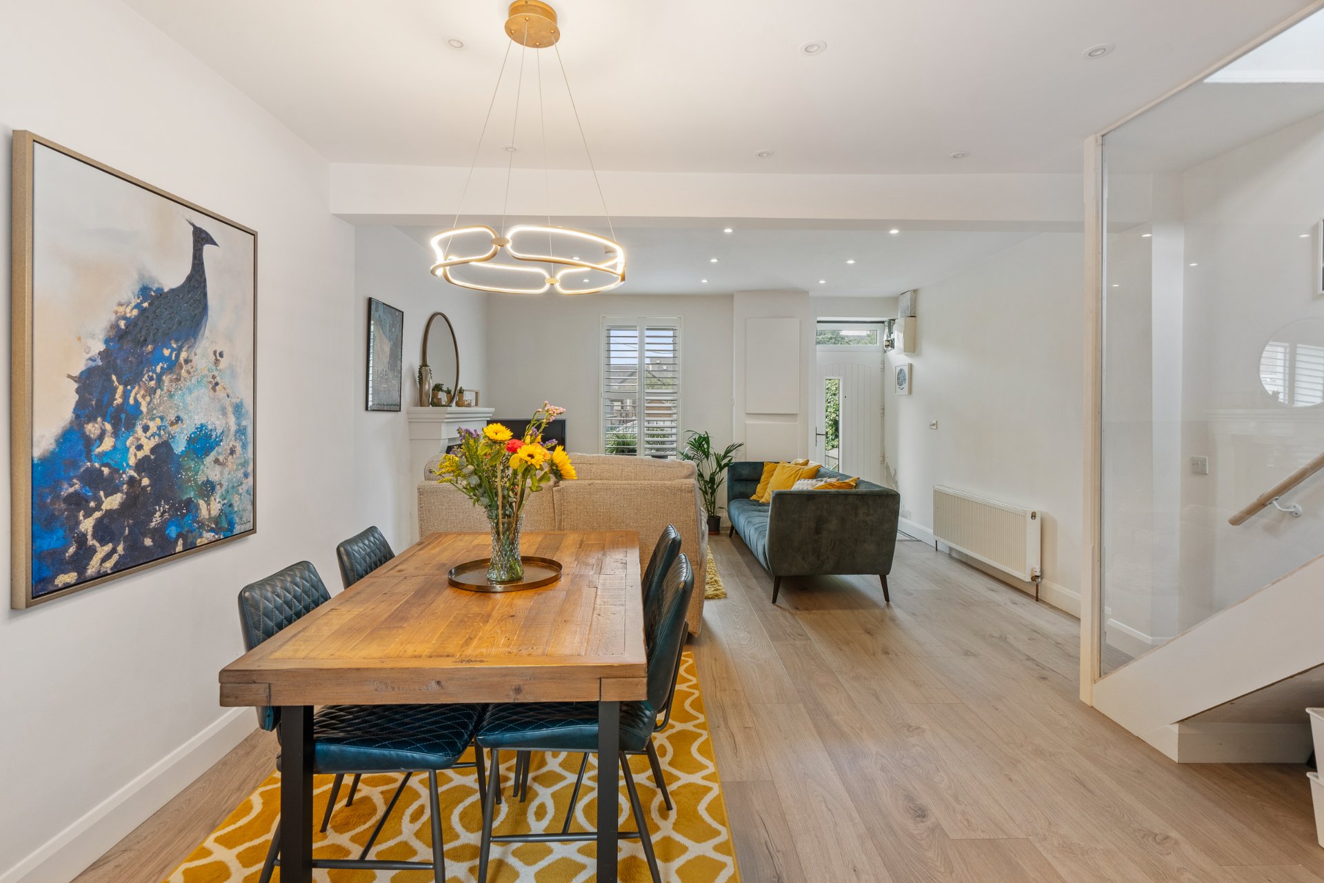 The dining and living space with a glass stair balustrade and access to the rear garden.