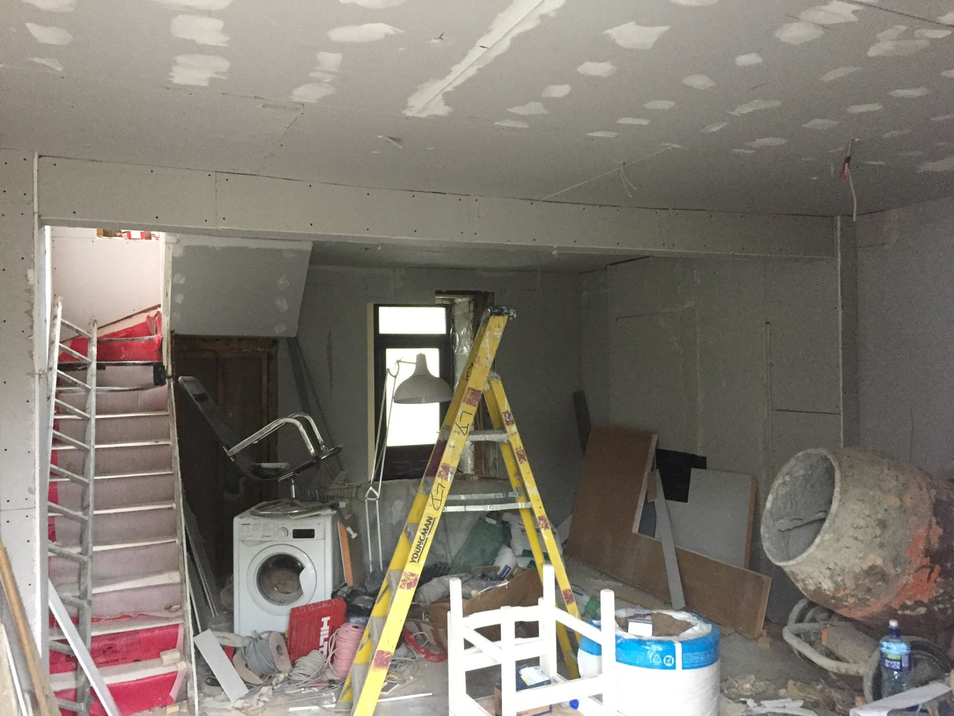 The house at first fix — new plasterboard up, the staircase in and a cement mixer on site.