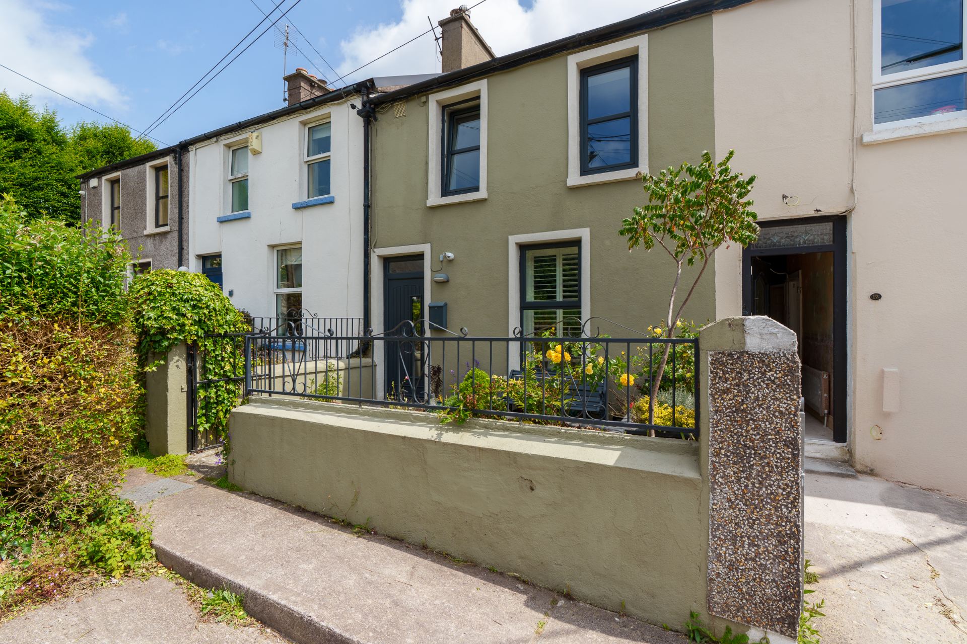 The renovated front of a terraced house at Alexandra Villas, Cork — smooth render and dark grey windows.