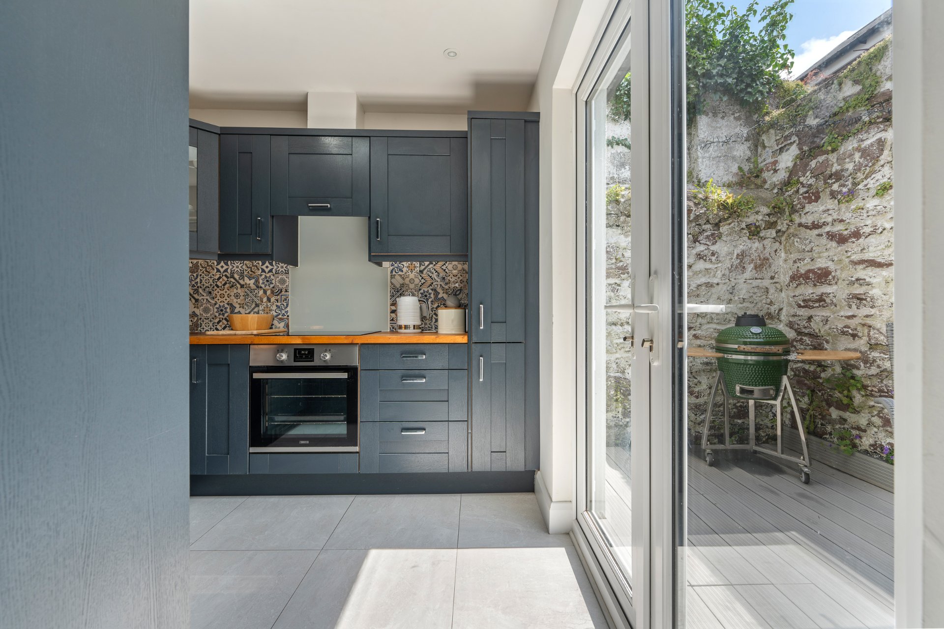The renovated navy shaker kitchen with oak worktops and French doors onto the rear courtyard.